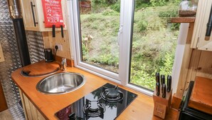 A kitchen with a stainless steel sink, a black stove, and wooden countertops. - The Hamper (Carmarthen)