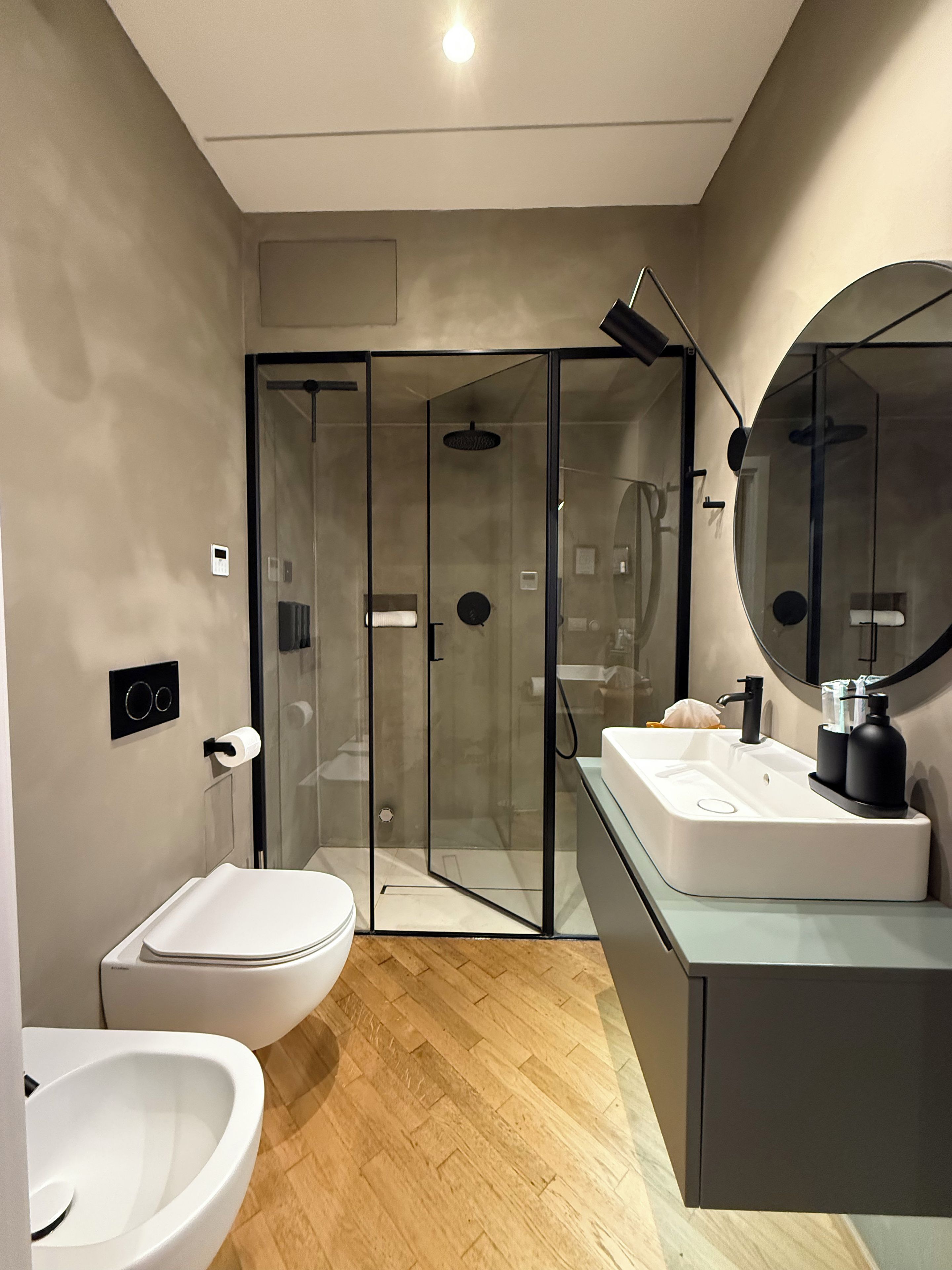 A modern bathroom with a glass-enclosed shower, a white toilet, a bidet, and a vanity with a mirror.