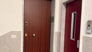 A wooden door with a keypad lock, a red door with a window, and a tiled floor. - Cosy (Bari)