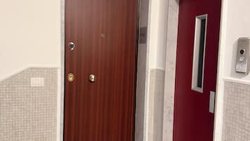 Una porta in legno con serratura a combinazione, una porta rossa con una finestra e un pavimento piastrellato.