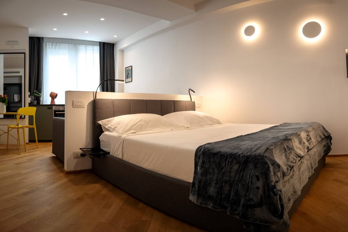 Un dormitorio moderno con una cama, mesita de noche y televisor montado en la pared.