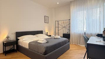 Ein Schlafzimmer mit Bett, Nachttischen, einem Schreibtisch und einem Sessel.