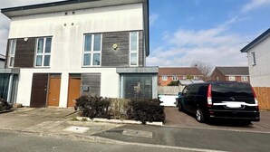 En toetages boligbygning med moderne arkitektur, karakteriseret ved et fladt tag, store vinduer og en garage.