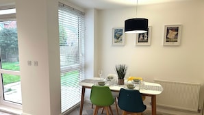 Et spiseområde med et bord dækket til to personer, en potteplante og en radiator.