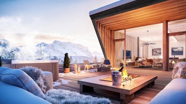 Een modern buitenleven met een houten terras, zitgedeelte en een vuurplaats.