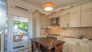 A kitchen with wooden cabinets, a dining table, chairs, a stove, and a sink.