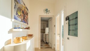 A narrow hallway with a kitchen visible in the background, a painting on the wall, and a decorative octopus sculpture.