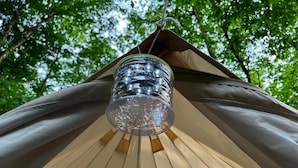 A clear glass lantern hanging from a wooden structure. - Large Group Glamping Tent Sleeps 8Yokahu Bell Tent, near Concerts, Casino, Falls (Harris)