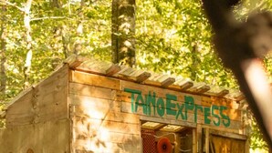 A wooden structure labeled 'TattoExpress' with a door, a chair, and various items inside. - Large Group Glamping Tent Sleeps 8Yokahu Bell Tent, near Concerts, Casino, Falls (Harris)