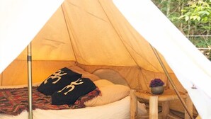 A tent with a bed, pillows, a small stool, and a potted plant. - Riverfront Bell Tent Glamping -15 minutes to Bethel Woods Concerts (Harris)