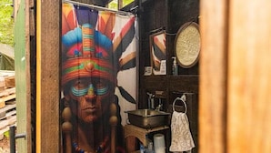 A small, rustic bathroom with a shower curtain featuring a tribal design, a sink, and a mirror. - Riverfront Bell Tent Glamping -15 minutes to Bethel Woods Concerts (Harris)