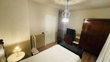A hotel room with a bed, a desk, a chair, a television, and a wardrobe.