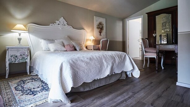 A bedroom with a large bed, two bedside tables, a chair, a dresser, and a mirror. - CR BnB Rozzano (Rozzano)