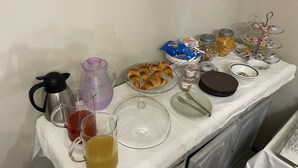 A breakfast buffet setup with various food items, a coffee maker, and a water dispenser on a table. - CR BnB Rozzano (Rozzano)