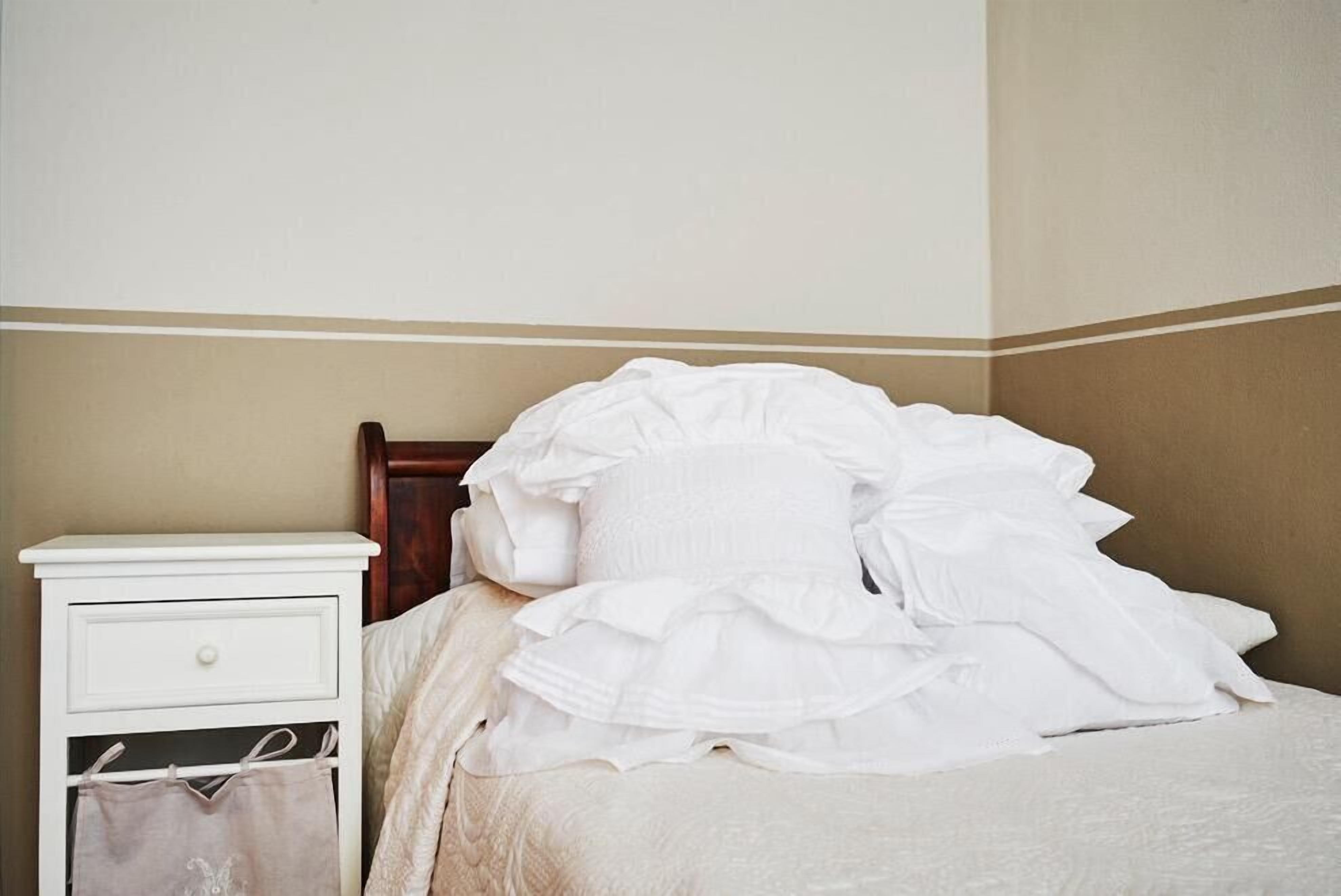 A bedroom with a bed, a nightstand with a drawer, and a hanging bag.
