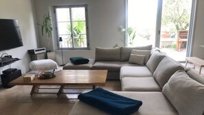 A modern living room with a large beige sectional sofa, a wooden coffee table, and a television on the left. - Mas Joseph amid vineyards and olive groves, 7 minutes from downtown Aix-en-Provence (Venelles)
