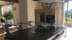 A modern kitchen with a central island, stainless steel appliances, and a large window providing natural light. - Mas Joseph amid vineyards and olive groves, 7 minutes from downtown Aix-en-Provence (Venelles)