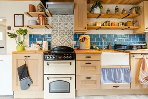 A kitchen with wooden cabinets, a stove, oven, and a blue tiled backsplash.