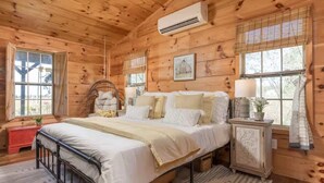 A wooden cabin bedroom with a bed, bedside tables, and a window. - Liberty Lodge Countryside Stay! Hot Tub, Sunsets (Valley Head)