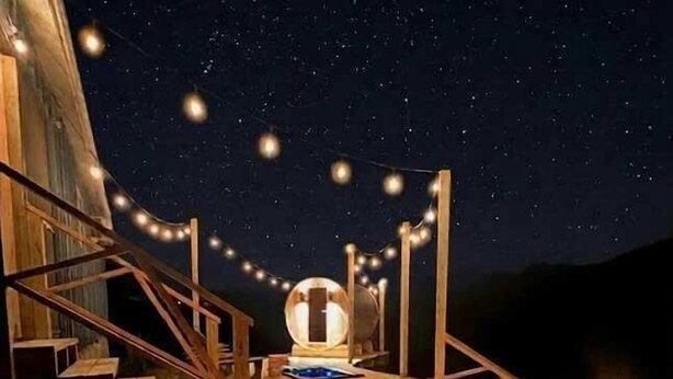 A wooden deck with a circular seating area, string lights, and a fire pit. - Liberty Lodge Countryside Stay! Hot Tub, Sunsets (Valley Head)