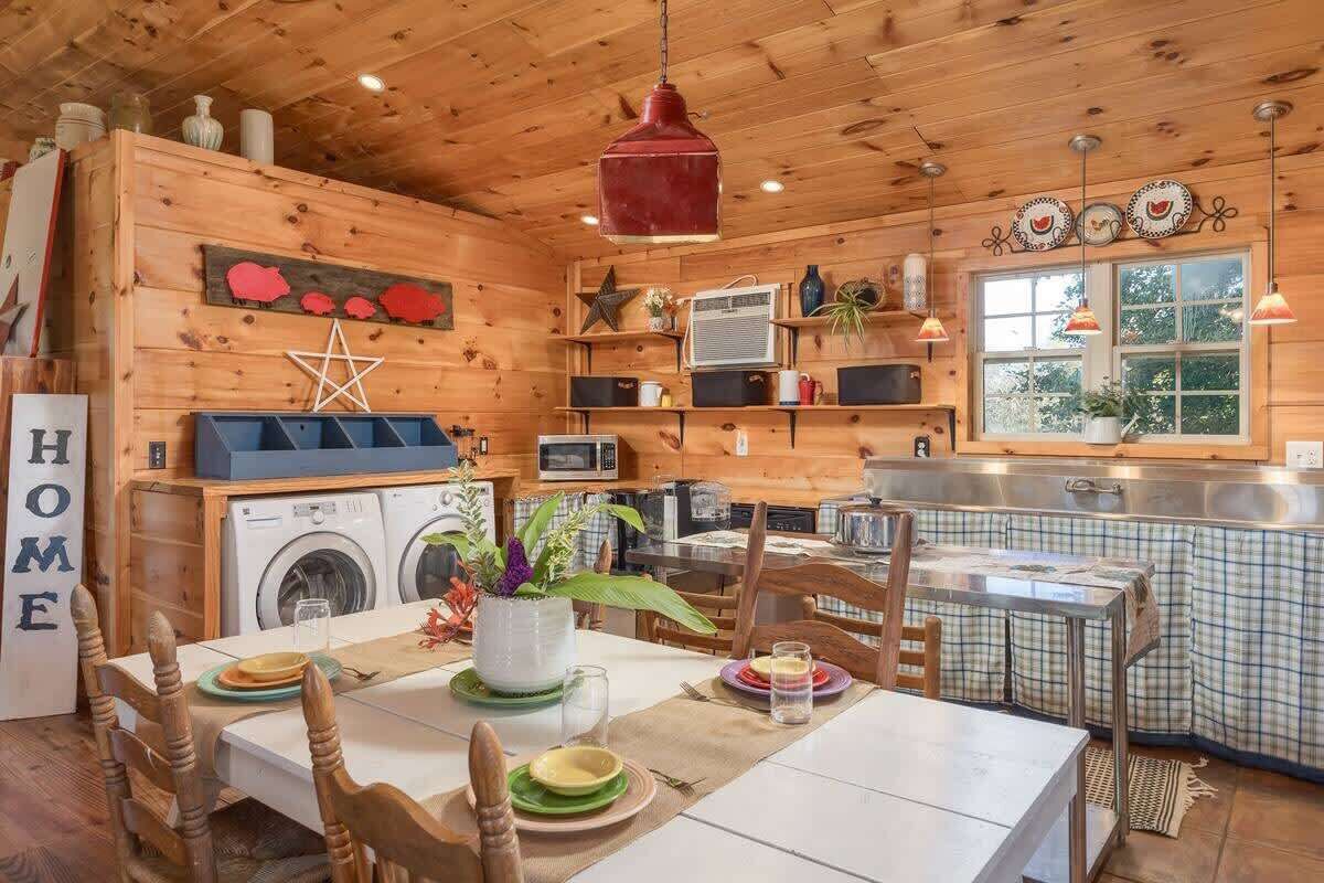 Una cocina acogedora de estilo cabaña, con paredes de madera, zona de comedor y lavadora.