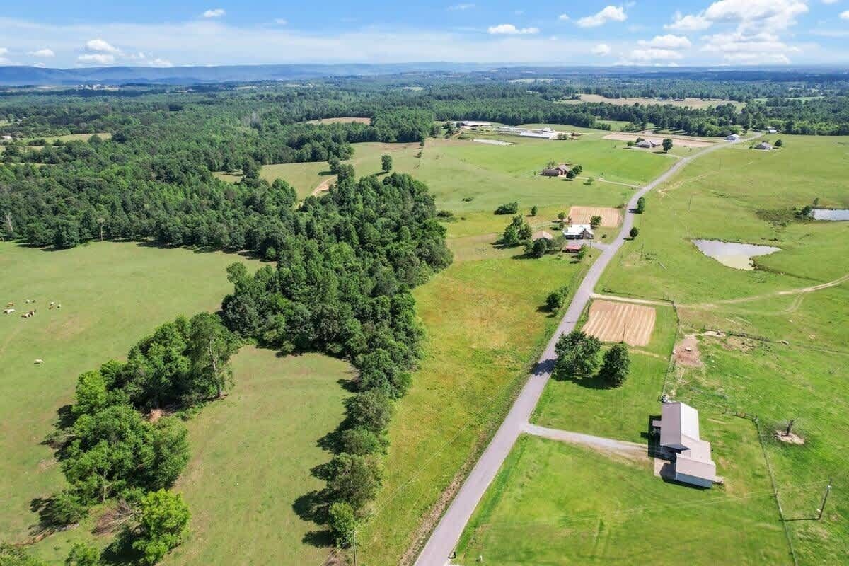 Een luchtbeeld van een landelijk gebied met velden, bomen en enkele gebouwen.