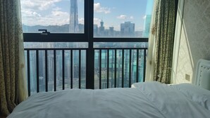 A hotel room with a large window offering a cityscape view, a bed, and curtains. - New CBD high-rise 3-brm LOFT, Huaxun Center, Luohu (Shenzhen)