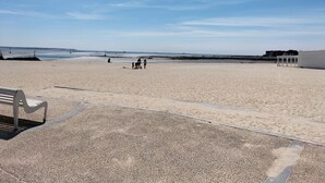 Une plage avec un banc et quelques personnes au loin.