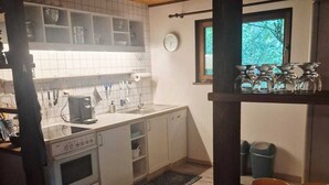 Une cuisine de taille réduite avec des meubles blancs, une cuisinière et une fenêtre.