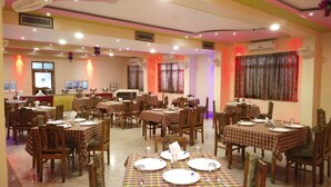 Een restaurant met meerdere tafels voor diners, stoelen en een toonbank met een display.