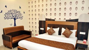 Een hotelkamer met een groot bed, een houten hoofdbord en een bruine leren bank.