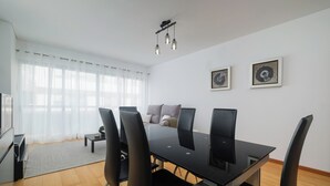A modern dining area with a black table and chairs, a sofa, and a TV. - HALT Apartment (Ponta Delgada)