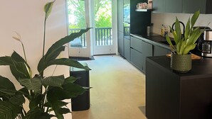Une cuisine moderne avec des meubles de couleur sombre, un plan de travail noir et une plante en pot.