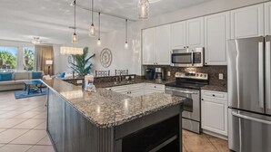 A modern kitchen with granite countertops, stainless steel appliances, and pendant lighting. - Crescent 109 (Miramar Beach)