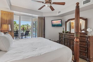 Ein Hotelzimmer mit einem großen Bett, einem Deckenventilator, einem Fernseher, einem Schminktisch und Blick ins Freie.