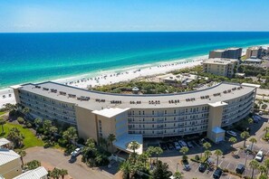 Ein großes, gebogenes Hotel mit mehreren Etagen und Blick auf den Strand.