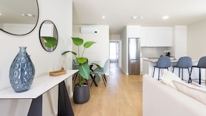 A modern kitchen with white cabinets, a stainless steel refrigerator, and a dining area with a table and chairs. - Modern apartment near the sea in Tenerife. (Abades)