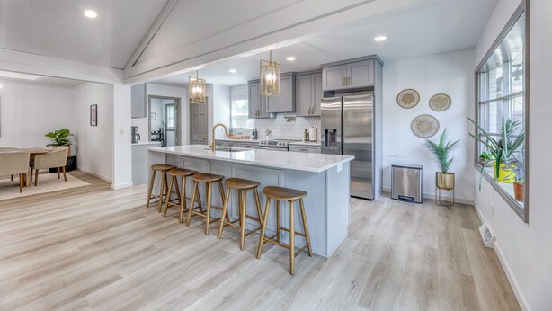 A modern kitchen with a central island, bar stools, stainless steel appliances, pendant lighting, and a view through a large window. - Upscale Fishers Getaway/Hot Tub/Peaceful/Quiet! (Fishers)