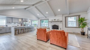 A spacious kitchen with grey cabinets, a central island with stools, and a large window providing natural light. - Upscale Fishers Getaway/Hot Tub/Peaceful/Quiet! (Fishers)