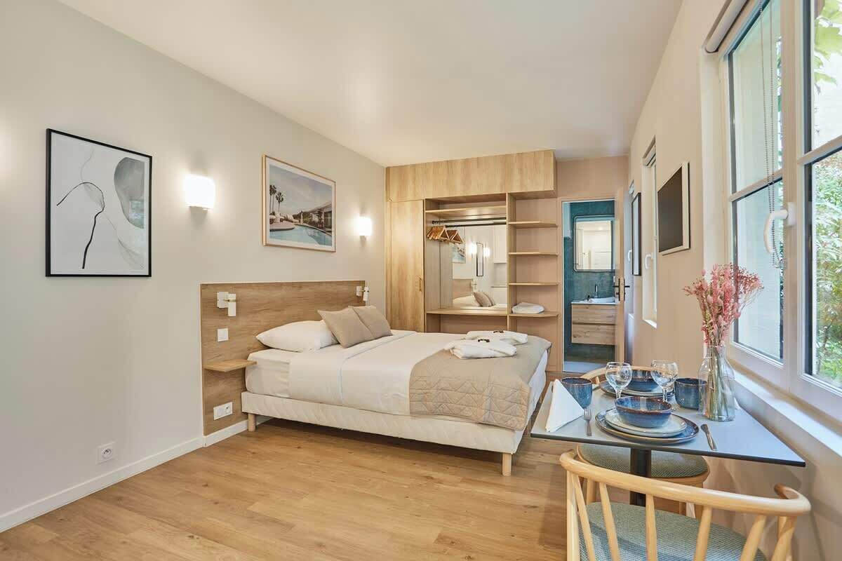 A bedroom with a bed, bedside table, and a view of the outside.