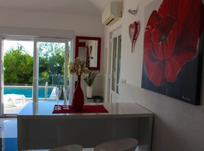 A modern kitchen with a large window, a red vase with flowers, and a red poppy painting on the wall. - Seafront Apartment Sea Relax With Private Pool (Omis)
