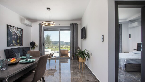 Ein modernes Hotelzimmer mit Essbereich, einem Bett und einem Balkon mit Blick.