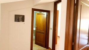 A hallway with a wooden door leading to a bathroom. - [Caracol 4] Apartment in the middle of the countryside with terrace (Orosei)