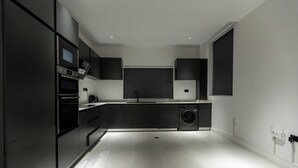 A modern kitchen with built-in appliances, a washing machine, and a large window.