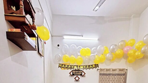 Una habitación con mostrador de recepción, un sofá y una pared decorada con globos y un cartel.