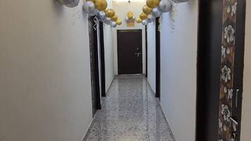 A hallway with a marble floor and walls, decorated with gold and silver balloons.