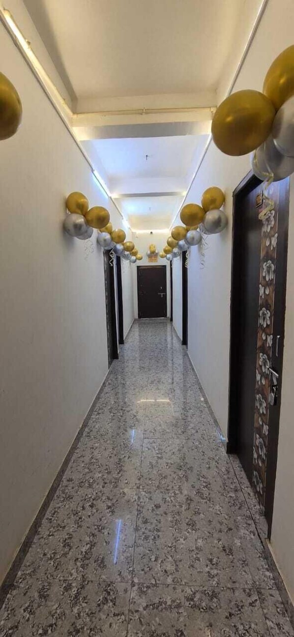 A hallway with a marble floor and walls, decorated with gold and silver balloons.