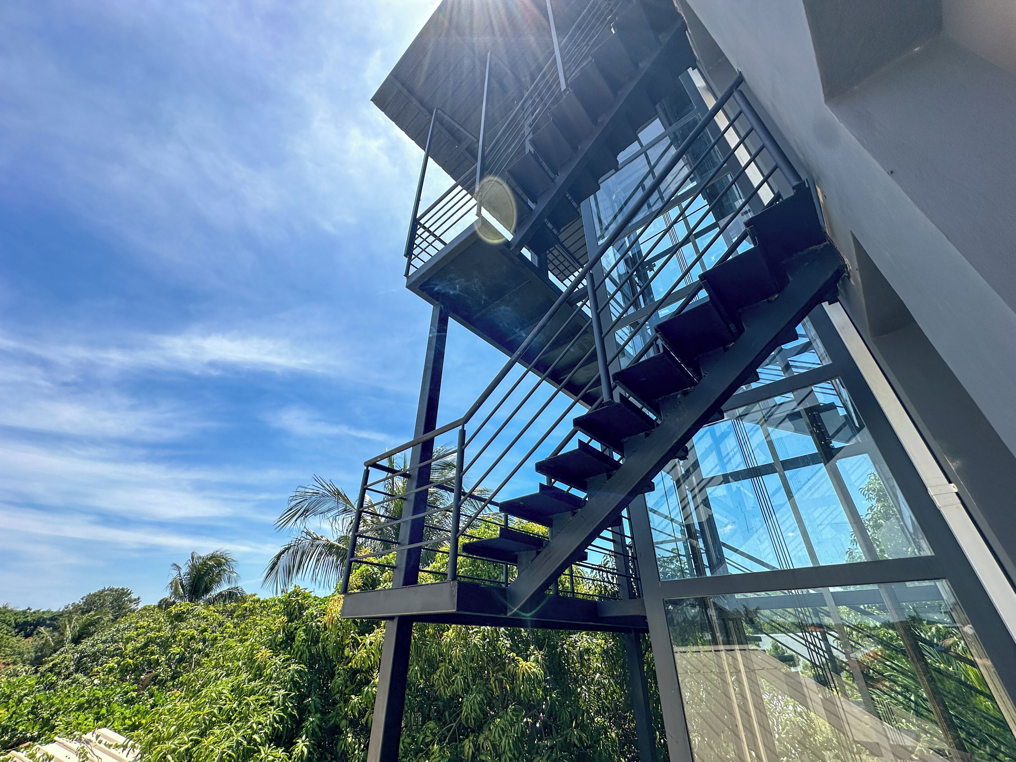 A modern building with a glass facade and a metal staircase leading to an upper level.