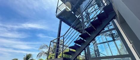 A modern building with a glass facade and a metal staircase leading to an upper level.