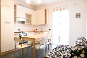 A compact kitchen with a central island, white cabinetry, and a dining area with chairs.